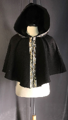 Cloak:3889, Cloak Style:Shaped Shoulder Cloak, Cloak Color:Black, Fiber / Weave:Double faced Wool and Cotton, Cloak Clasp:hook & eye, Hood Lining:self-lined cotton, Back Length:22", Neck Length:20", Seasons:Spring, Fall, Southern Winter, Note:Eye-catching black shaped shoulder<br>short cloak is 100% cotton on the 
inside,<br>100% wool on the outside, and features<br>a trim of silver and gold 
celtic beasties.<br>Closed with a black hook and loop,<br>it's a delightful and 
unique way<br>to warm your shoulders or for a child to wear..