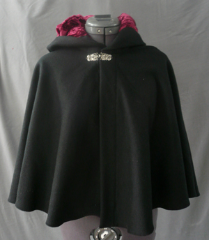 Cloak:1773, Cloak Style:Shaped Shoulder-Short, Cloak Color:Black, Fiber / Weave:Wool Cashmere, Cloak Clasp:Alpine Knot - Silvertone, Hood Lining:Cranberry Crushed Velvet, Back Length:20.5", Neck Length:20", Seasons:Winter, Fall, Spring.