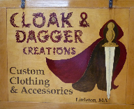 A photograph of the sign for Cloak & Dagger Creations, a company which creates historical recreation garments, custom clothes, medieval wear, custom wedding garments and other unique fashion items and accessories.
